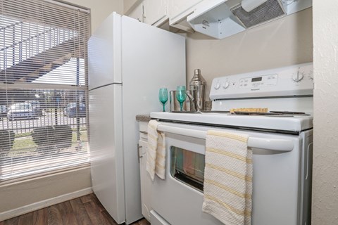 A white refrigerator and stovetop oven in a kitchen with a window at The Drake in Bossier City, LA
