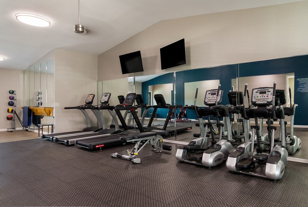 fitness center filled with cardio equipment and flat screen televisions at Dunwoody Pointe in Sandy Springs, GA