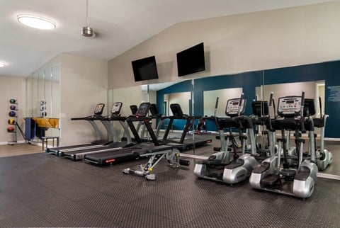 a room filled with cardio equipment and flat screen televisions