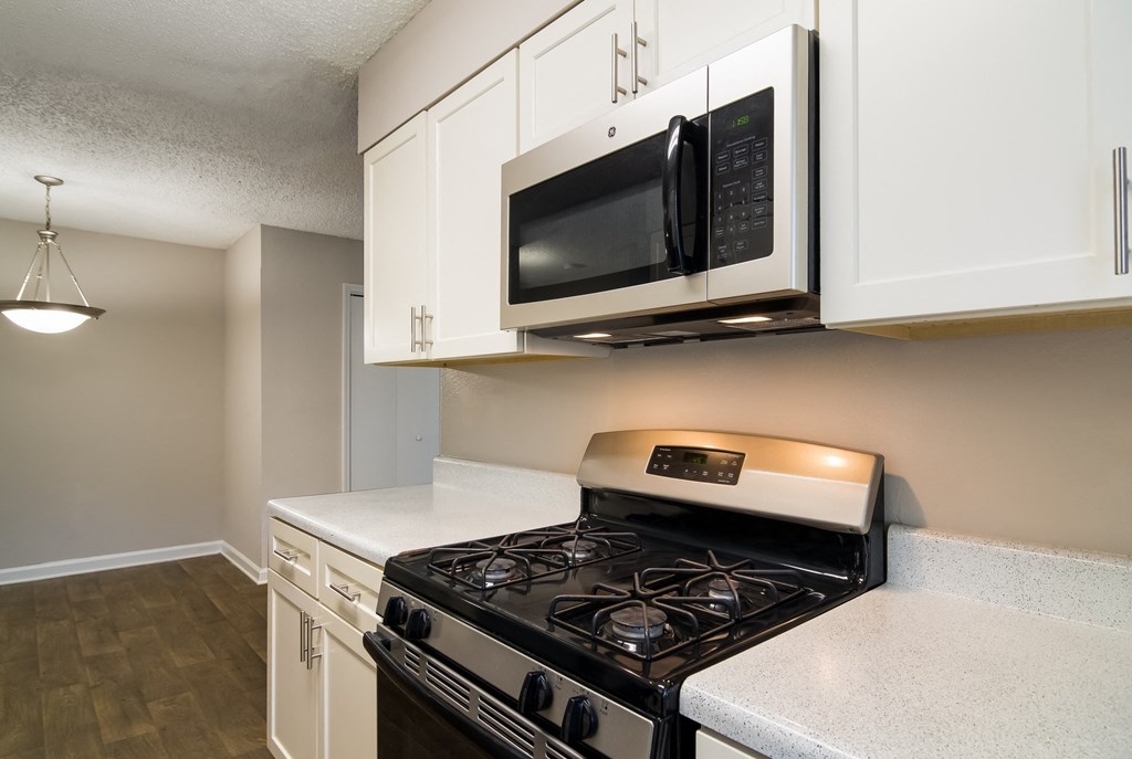 a kitchen with white cabinets and a black stove top oven at Dunwoody Pointe in Sandy Springs, GA