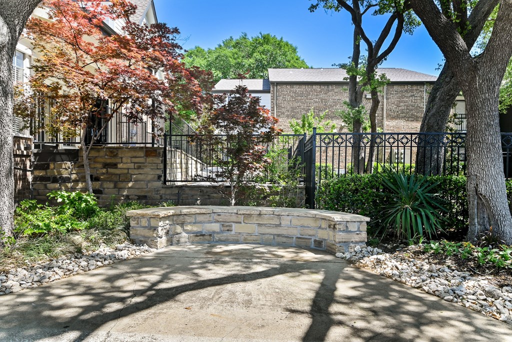 a retaining wall with a stone bench in front of a black wrought iron fence