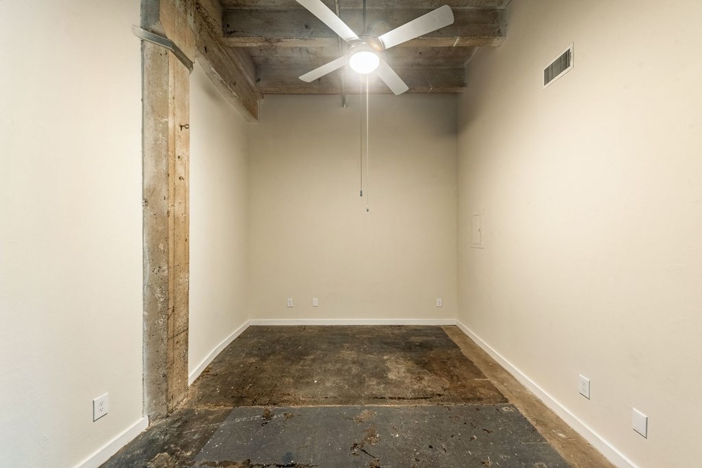a room with a concrete floor and a ceiling fan
