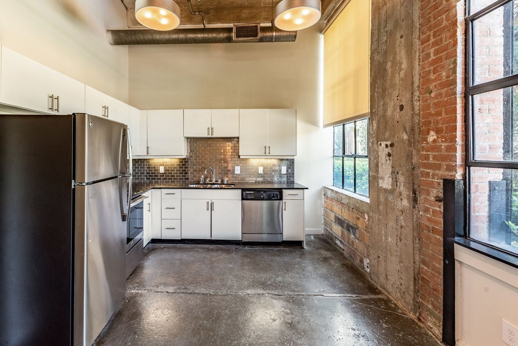 a kitchen with white cabinets and a brick wall