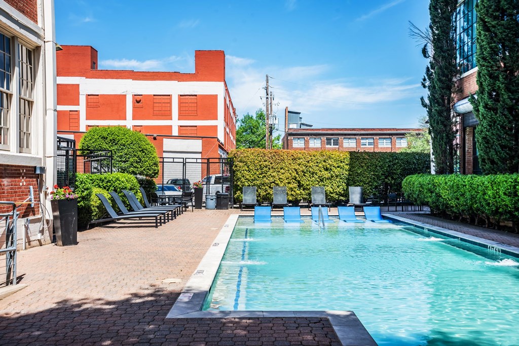 a swimming pool with chaise lounge chairs and a building in the background