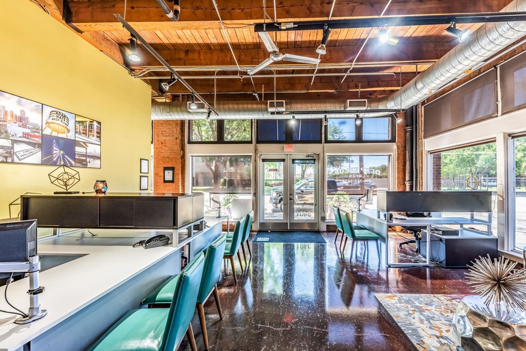 a room with a long counter with green chairs and a yellow wall with a lot of windows