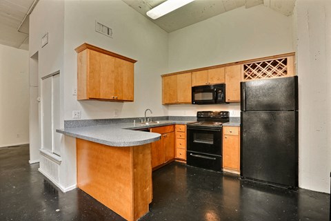 A kitchen with black appliances and wooden cabinets.