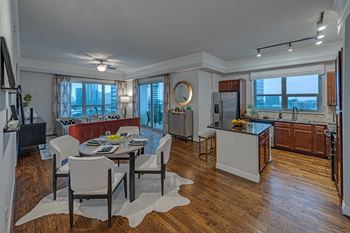 a kitchen and living room with hardwood floors and a large window at Dominion Post Oak in Houston, TX