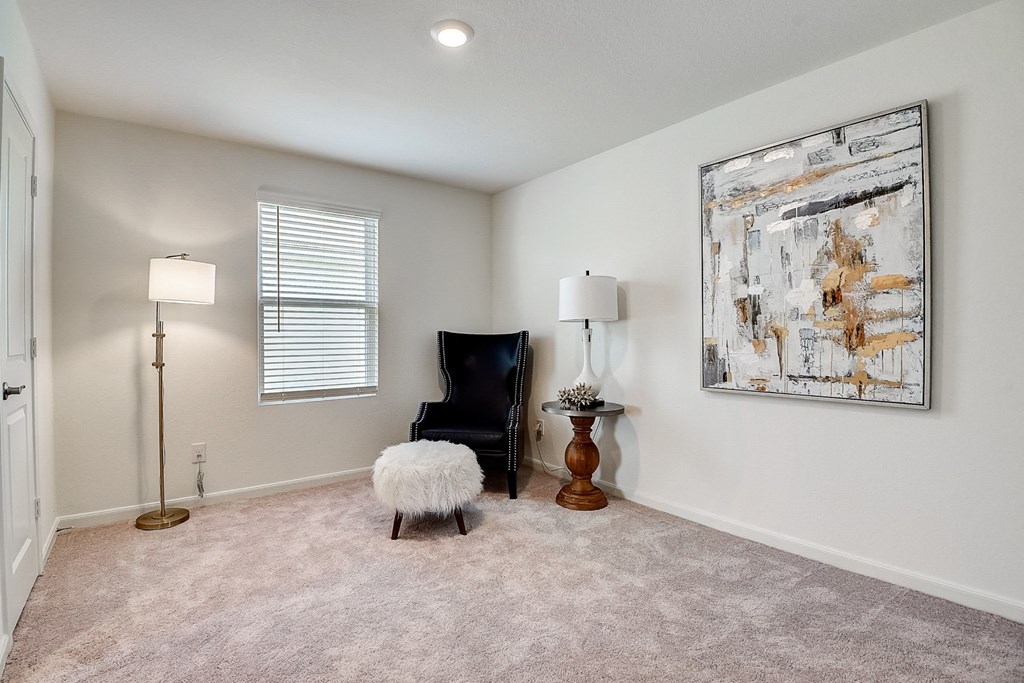 a bedroom with a chair and a lamp and a painting on the wall