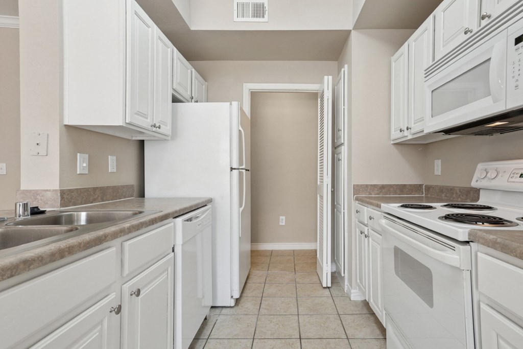 Edinburgh kitchen with white appliances and cabinets at Encore at Buckingham Apartments in Richardson, TX