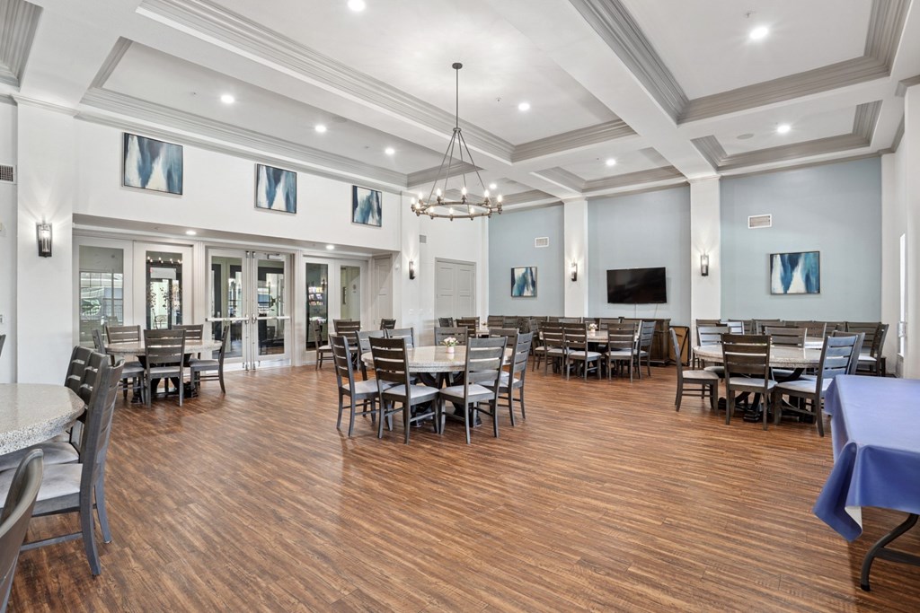 A large event room with a hanging chandelier and tables and chairs at Encore at Buckingham Apartments in Richardson, TX