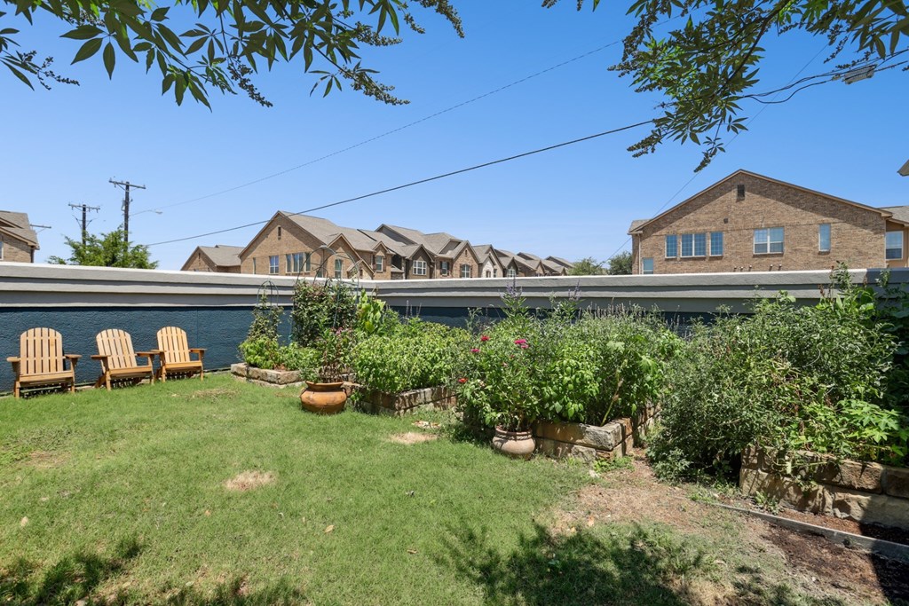 A garden with a lawn, a few chairs, and apartments in the background at Encore at Buckingham Apartments in Richardson, TX