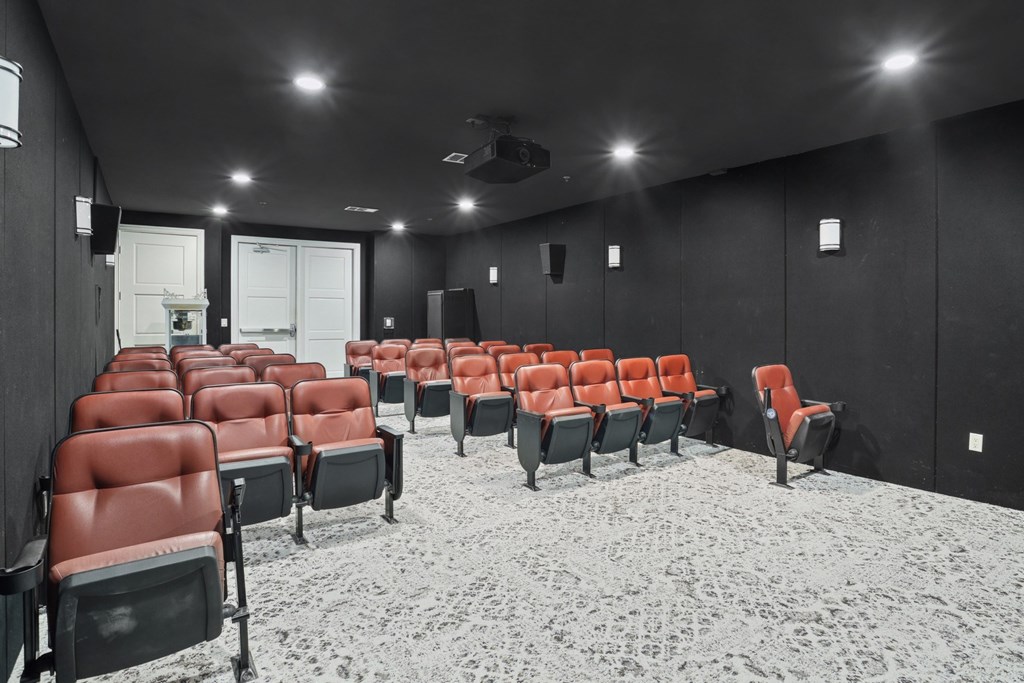 A movie theater with black walls and red seats at Encore at Buckingham Apartments in Richardson, TX
