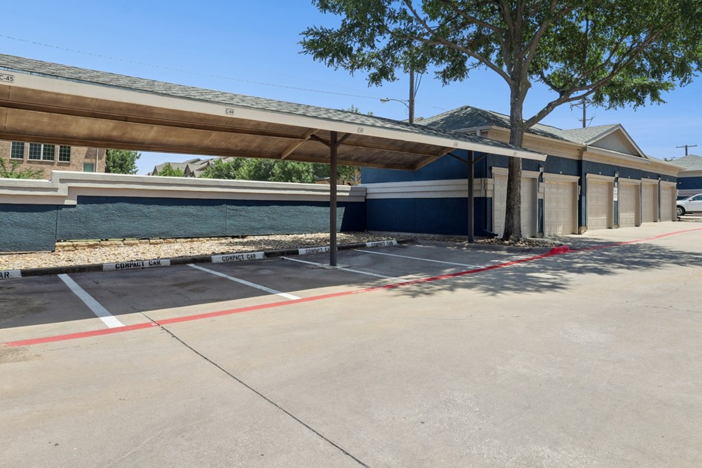 Reserved resident parking spots for compact cars with garages in the background at Encore at Buckingham Apartments in Richardson, TX