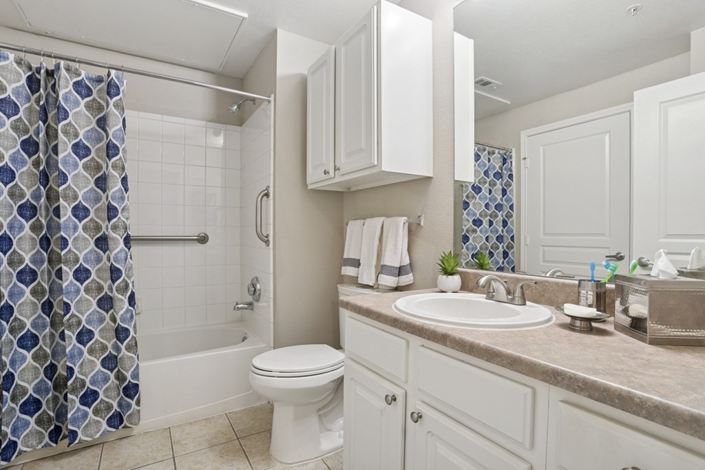 Windsor bathroom with a white toilet and a shower curtain and a sink at Encore at Buckingham Apartments in Richardson, TX