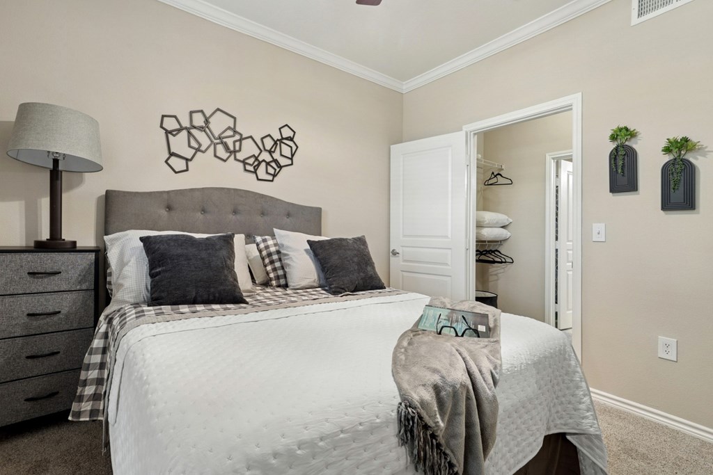 Windsor bedroom with a bed, closet, and wall decor at Encore at Buckingham Apartments in Richardson, TX