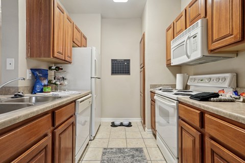 Windsor kitchen with wooden cabinets and white appliances at Encore at Buckingham Apartments in Richardson, TX