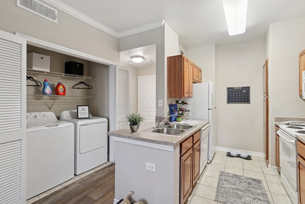 Windsor kitchen with a washer and dryer closet and white kitchen appliances at Encore at Buckingham Apartments in Richardson, TX
