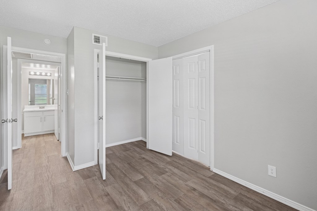 A3 bedroom with a white door, closet, and a wooden floor at Estelle Creek North Apartments in Irving, TX