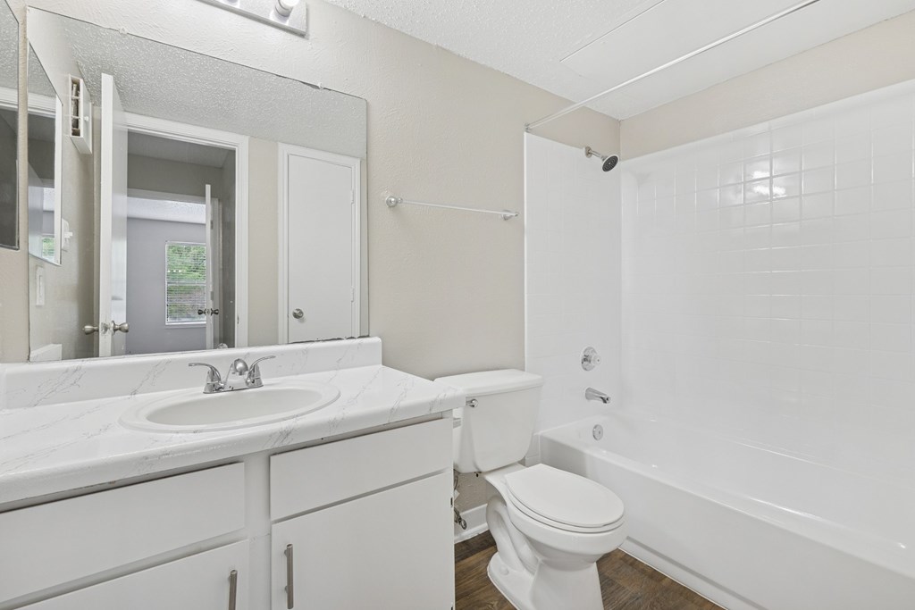 B1 white bathroom with a toilet, vanity sink, and bathtub at Estelle Creek North Apartments in Irving, TX