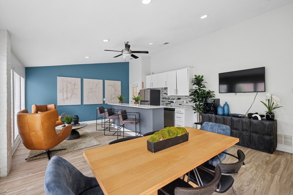 A modern clubhouse with a dining table and chairs, a kitchen, and a TV at Estelle Creek North Apartments in Irving, TX
