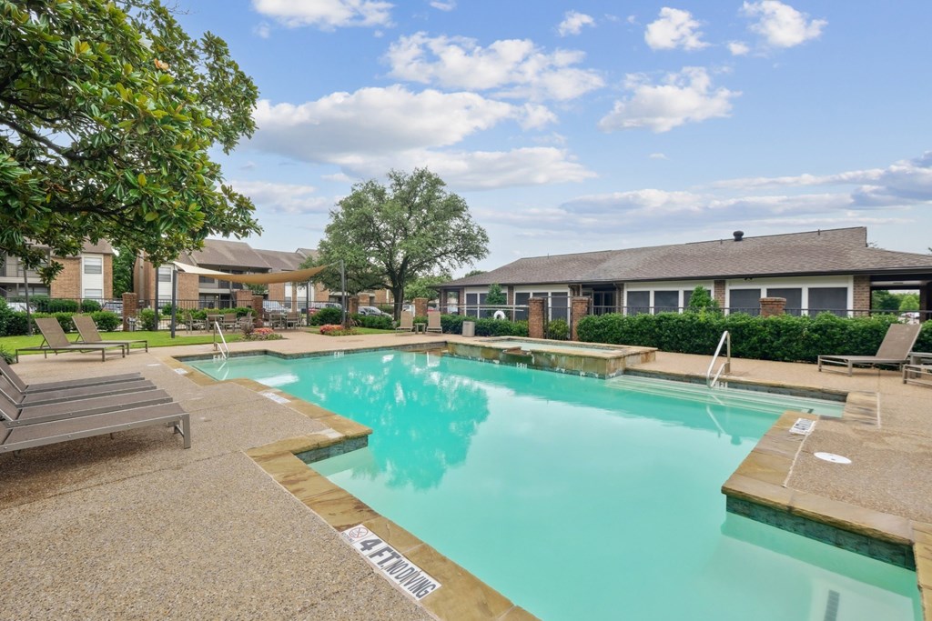 A sparkling pool with trees and the leasing office at Estelle Creek North Apartments in Irving, TX