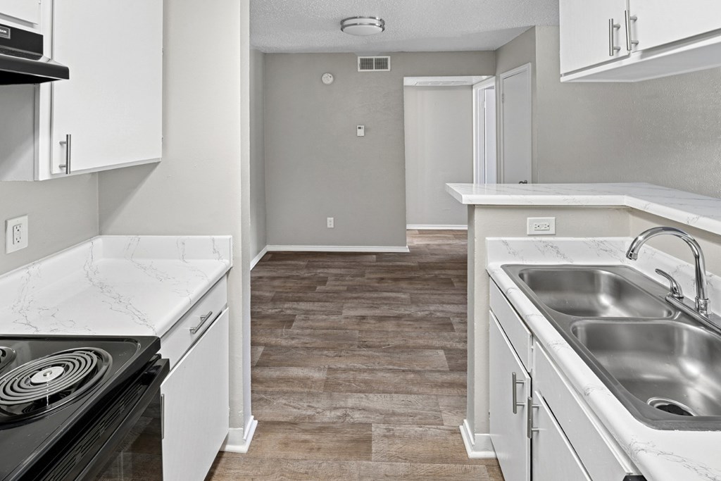 A2 kitchen with a stove top oven, sink, and white cabinets at Estelle Creek North Apartments in Irving, TX