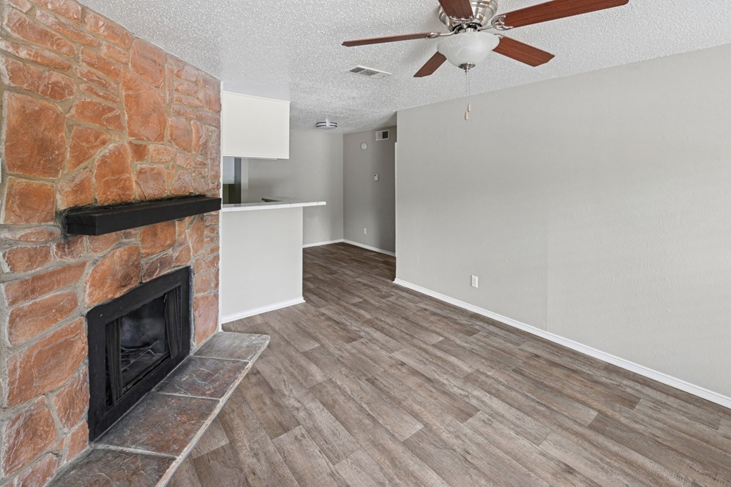A2 living room with a fireplace, wood floors, and a ceiling fan at Estelle Creek North Apartments in Irving, TX