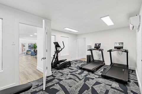 A room with treadmills and elliptical machines.