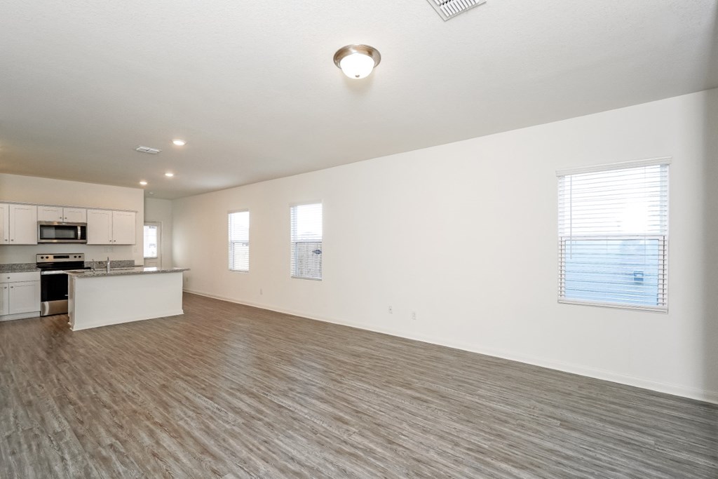 an empty living room with a kitchen in the background at Beacon at Meridian, San Antonio Texas