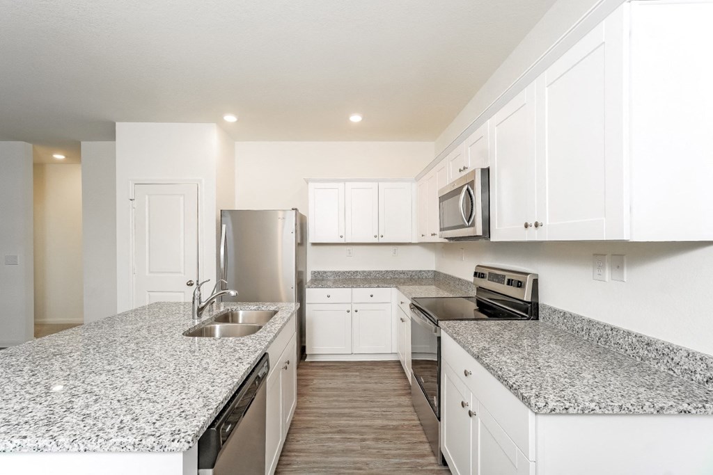a kitchen with white cabinets and granite countertops