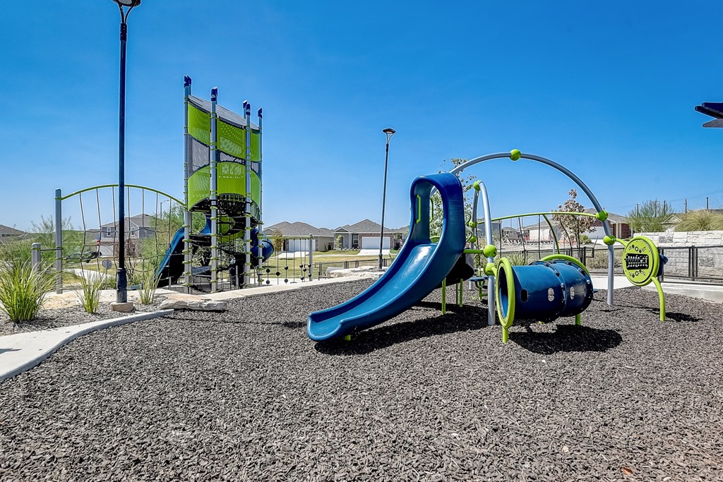 a playground with a blue slide and green playset at Beacon at Meridian, Texas