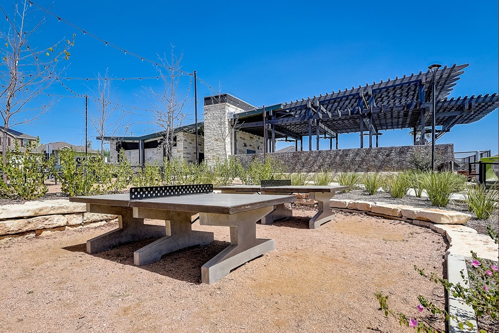 a picnic table with a ping pong table in front of a building at Beacon at Meridian, Texas