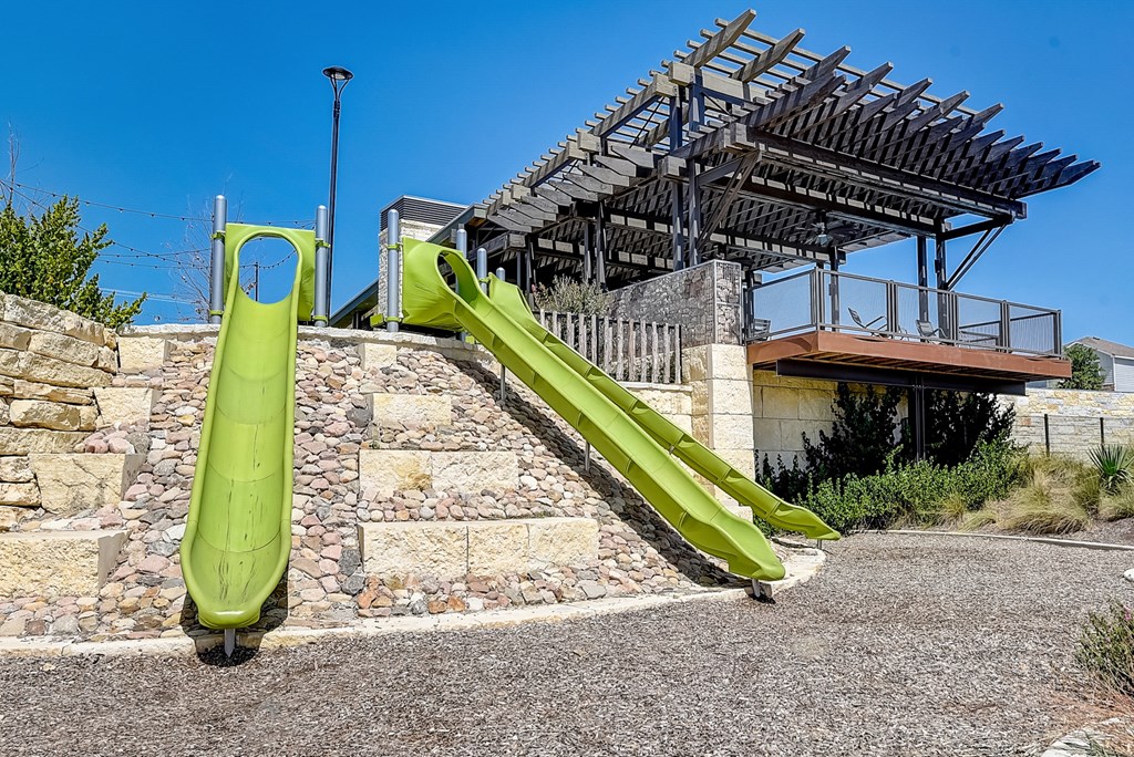 a green slide in front of a building at Beacon at Meridian, San Antonio, TX 78245