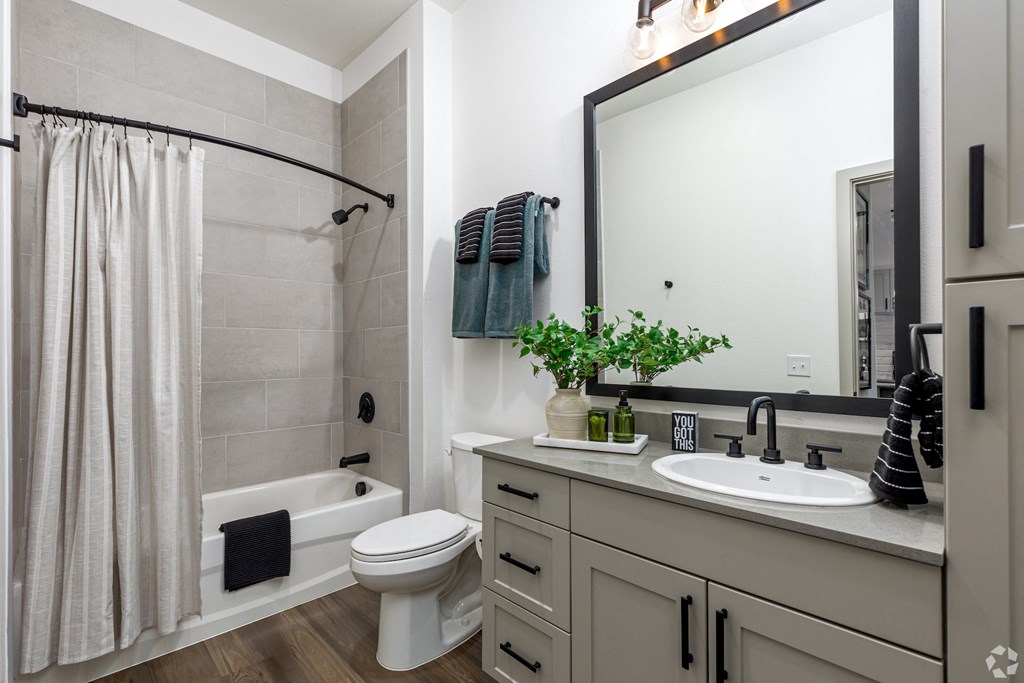 Model apartment bathroom with quartz countertop and large bathtub at Era apartments in Denton, TX