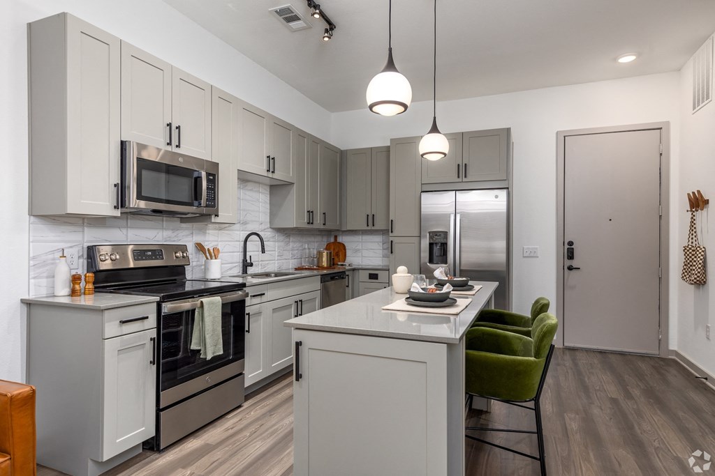 Model apartment kitchen with stainless steel appliances and quartz countertops at Era apartments in Denton, TX