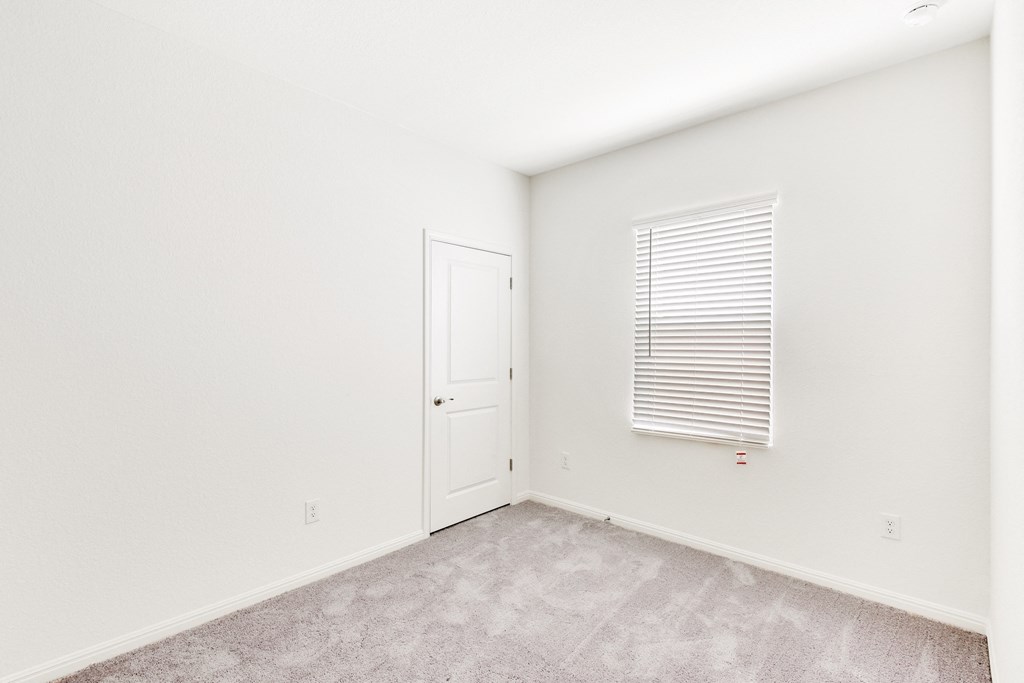 a bedroom with a door, a window and white walls