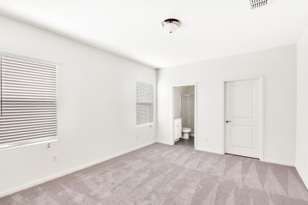 a master bedroom with white walls and a carpeted floor