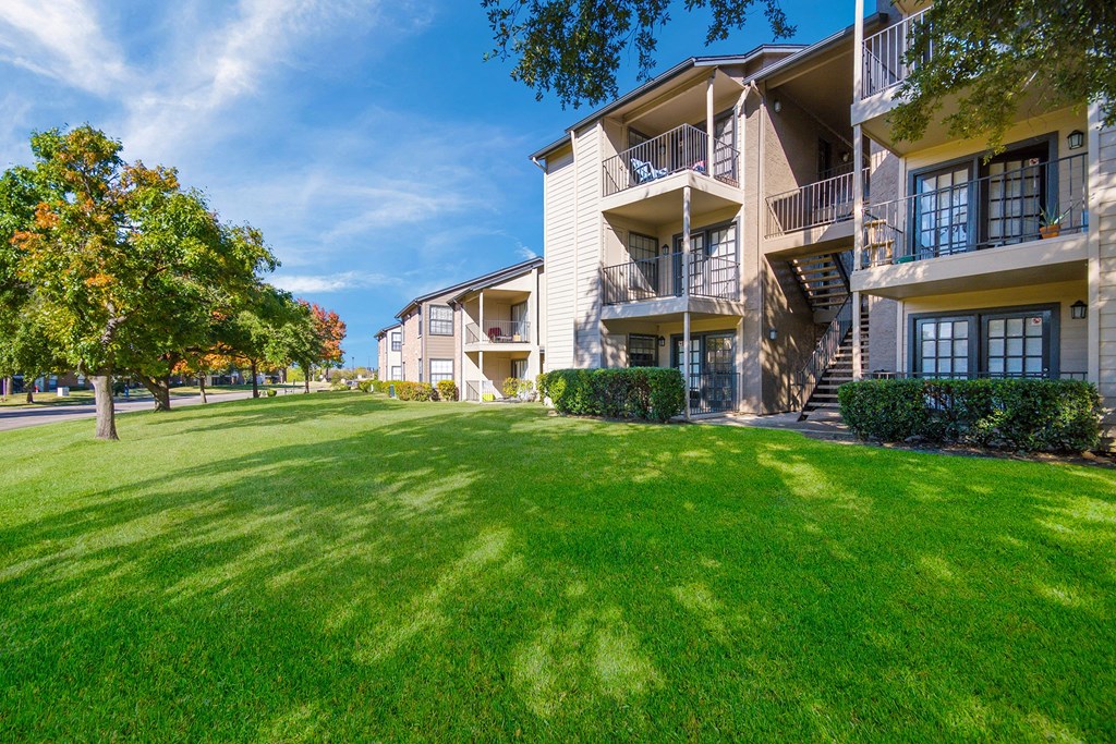 a large green lawn in front of an apartment building