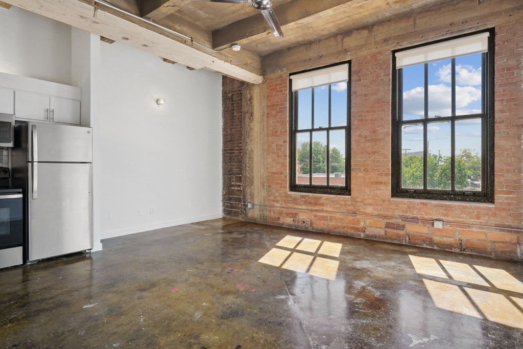 Farm and Ranch loft interior living area with polished concrete floors and brick accent wall | Deep Ellum Lofts in Dallas, TX