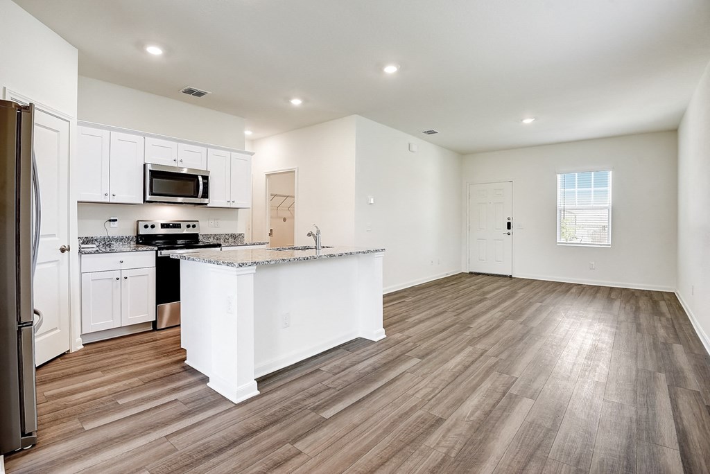 a kitchen and living room with hardwood floors and white walls at Beacon at Meridian, San Antonio Texas