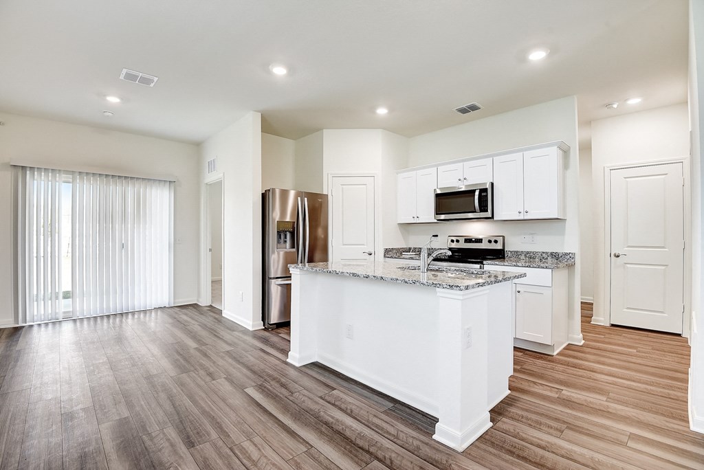 a kitchen and living room with a large island with granite countertops at Beacon at Meridian, San Antonio, TX