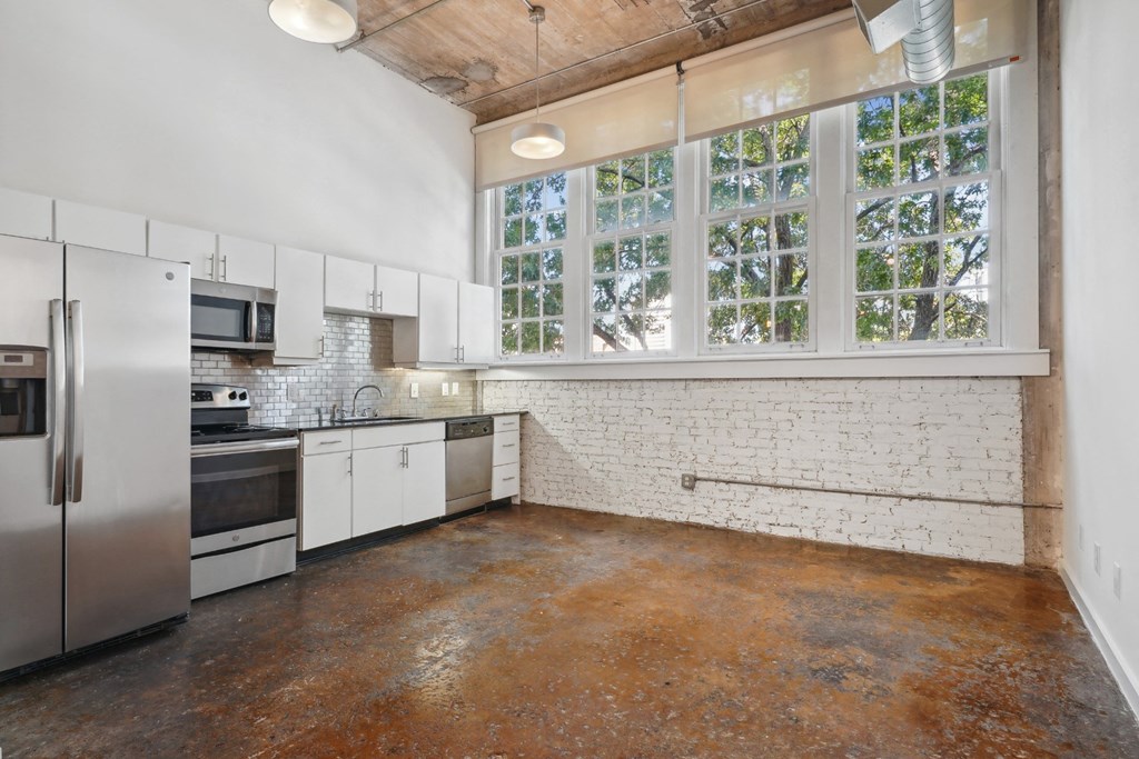 Futura Lofts kitchen with white cabinets and stainless steel appliances and large windows | Deep Ellum Lofts in Dallas, TX