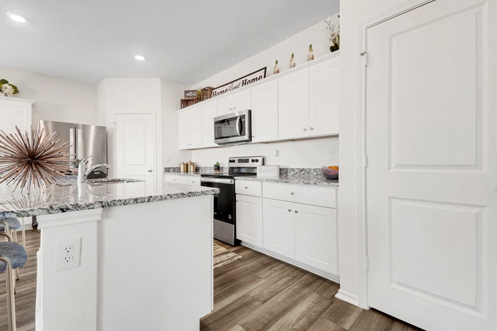 a kitchen with white cabinets and a large island with granite countertops at Beacon at Meridian, Texas, 78245