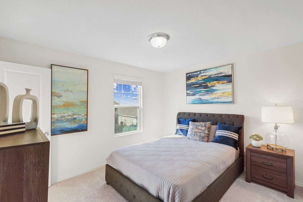 a bedroom with a bed and a dresser with a lamp at Beacon at Meridian, San Antonio