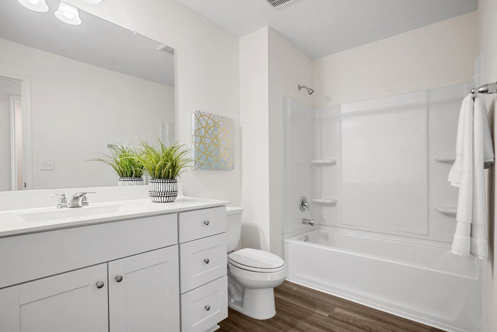 a bathroom with white cabinetry and a white toilet next to a white bathtub at Beacon at Meridian, San Antonio, TX 78245
