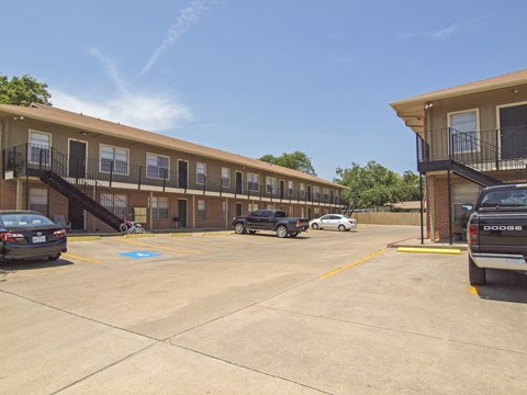 A parking lot with a building in the background and a truck parked in the foreground.