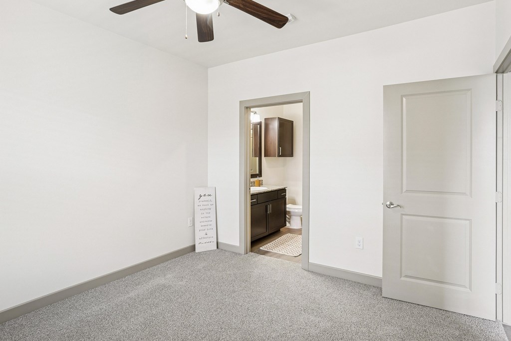 A bedroom with white walls, a closet, and a fan on the ceiling at GreenVue Apartments in Richardson, TX