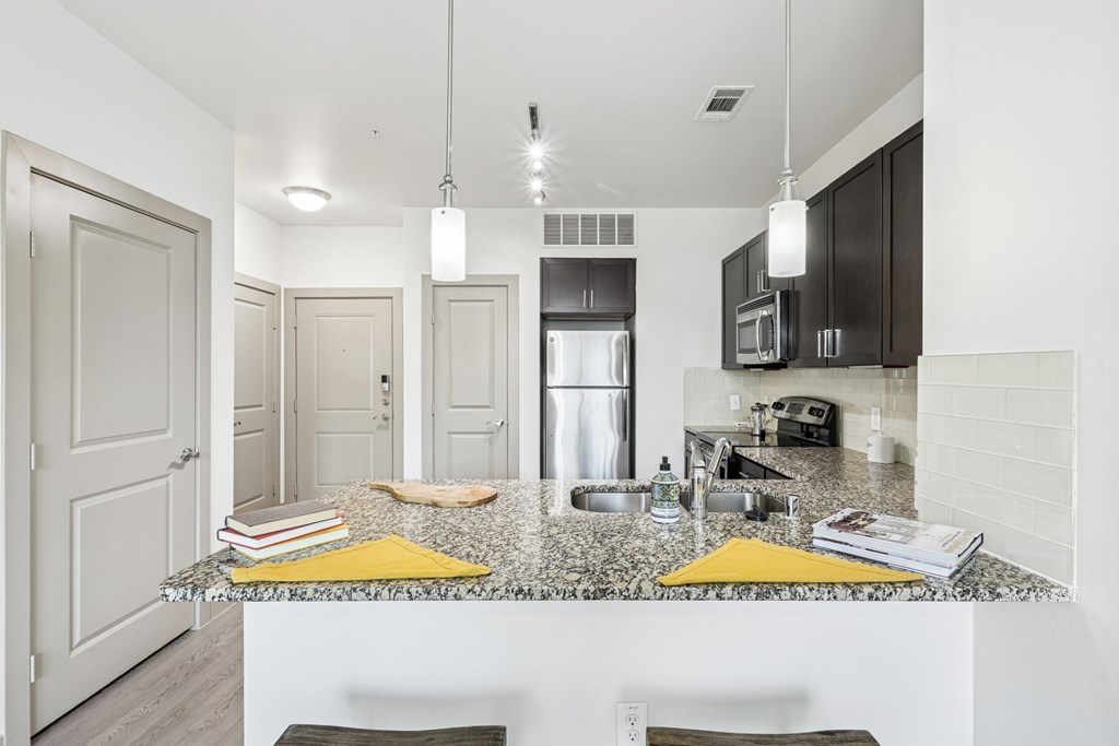 A kitchen with a granite countertop and dark cabinets at GreenVue Apartments in Richardson, TX