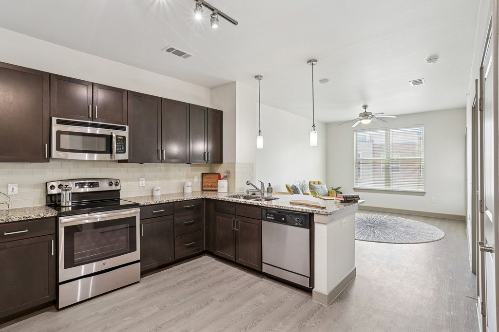 A modern kitchen with dark brown cabinets and stainless steel appliances at GreenVue Apartments in Richardson, TX
