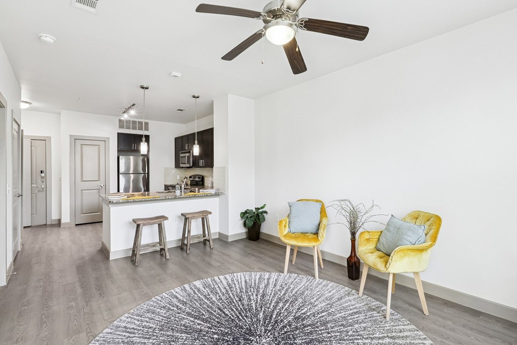 An open living room with a ceiling fan and grey rug at GreenVue Apartments in Richardson, TX